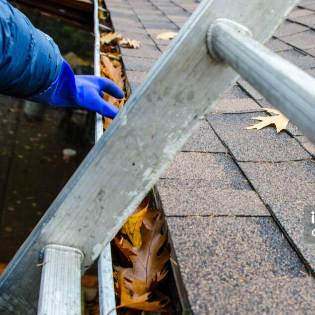 Gutter cleaning pink's home services Cleaning a gutter with on a ladder being done by pinks home services